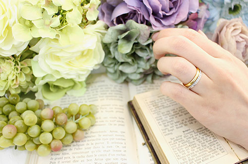 重ね付けした結婚指輪と本と花